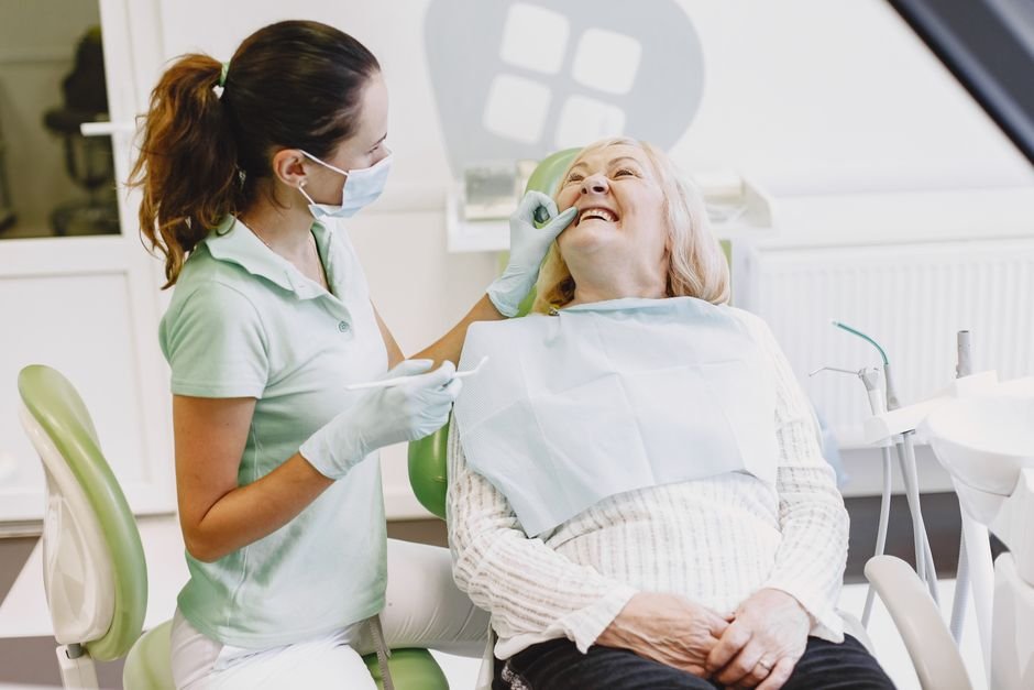 Dental hygienist examining a smiling patient's teeth during a routine checkup