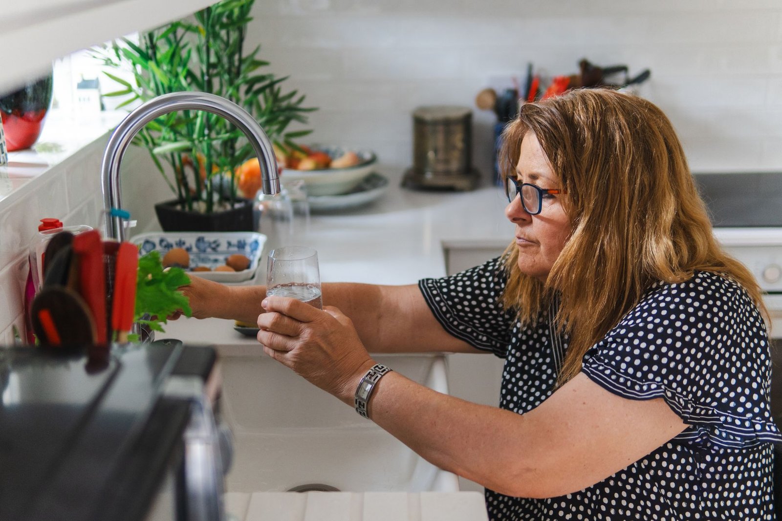 Woman filling a glass of water at a kitchen tap